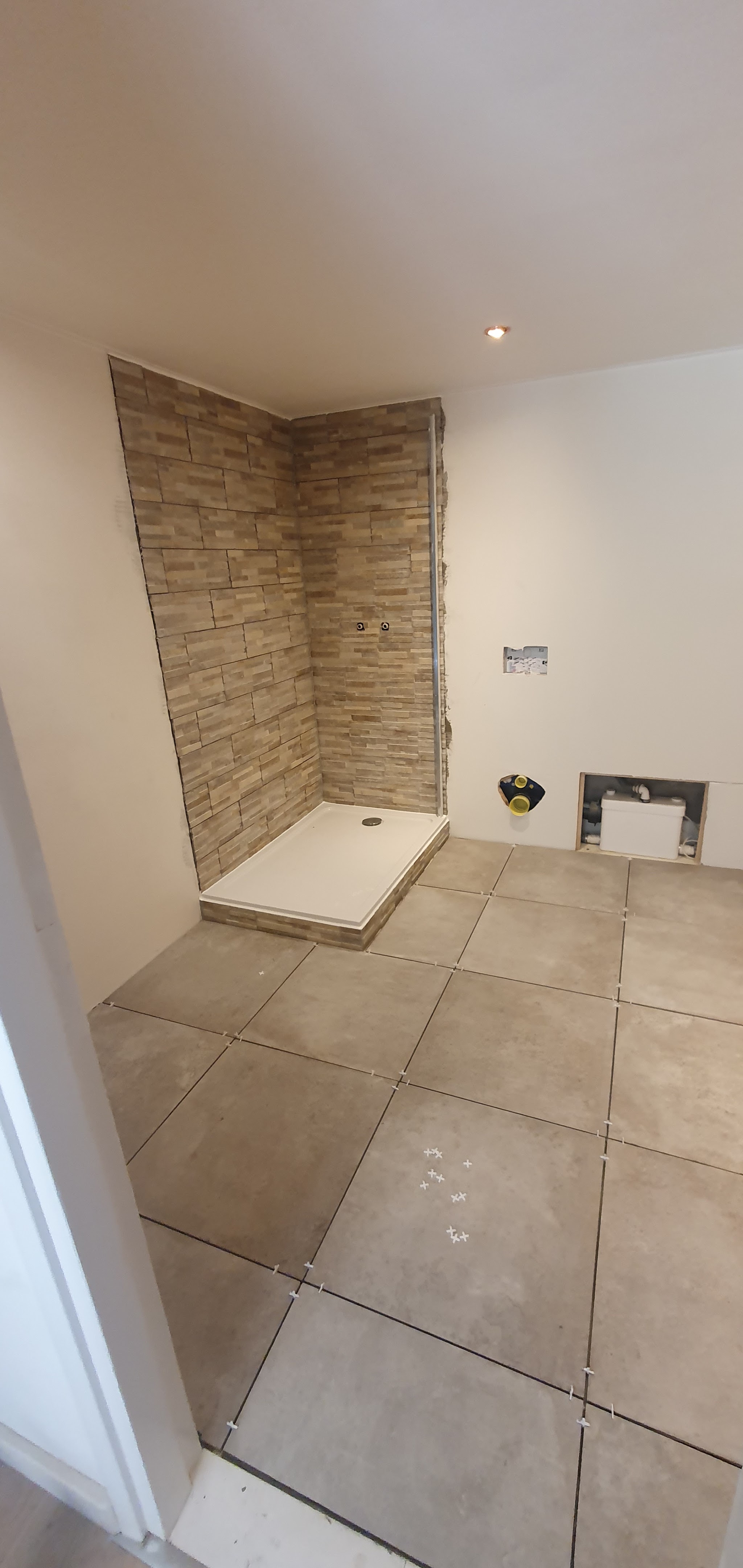 Badkamer halverwege het tegelwerk, met natuursteen in de douchehoek