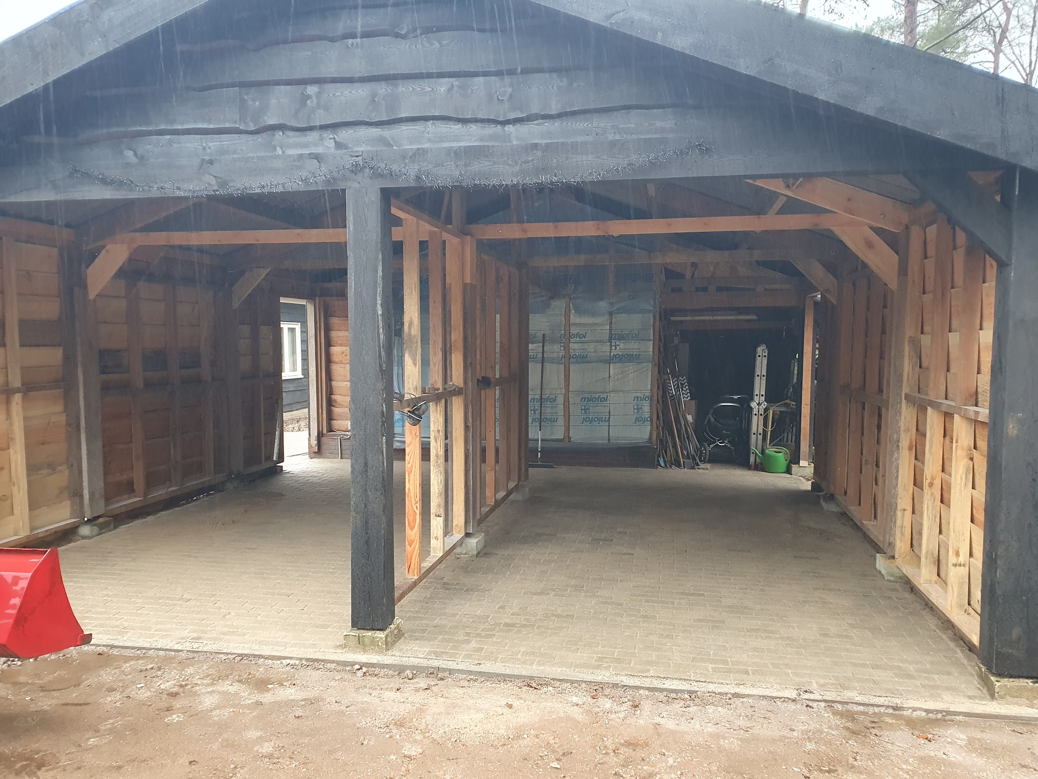 Binnenkant van een zwart gebeitste overkapping, met het houten spantwerk in het zicht